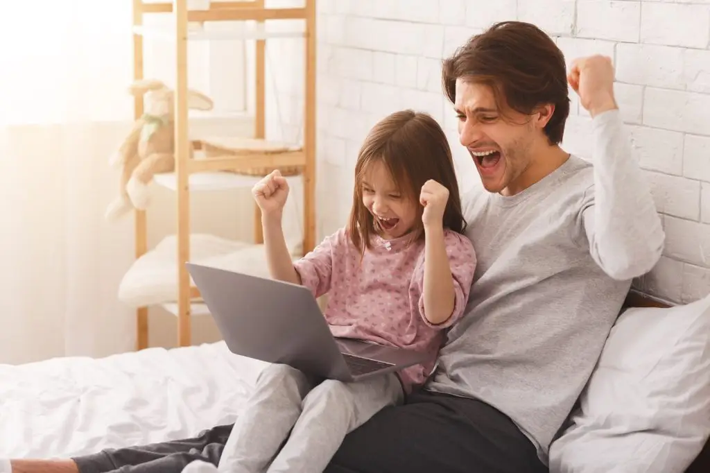 Dad and daughter celebrating online game.