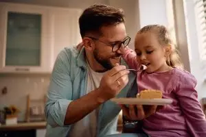 Father and daughter enjoying a piece of pie together.