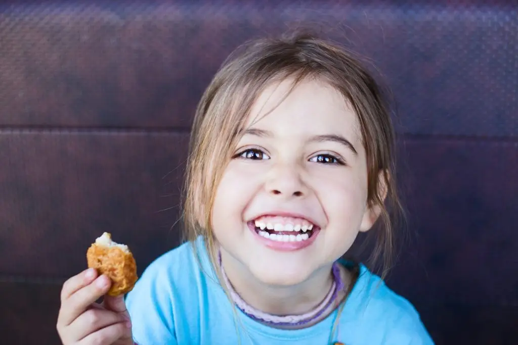Photo of a girl eating a chicken nugget