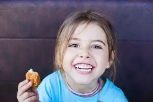 Photo of a girl eating a chicken nugget