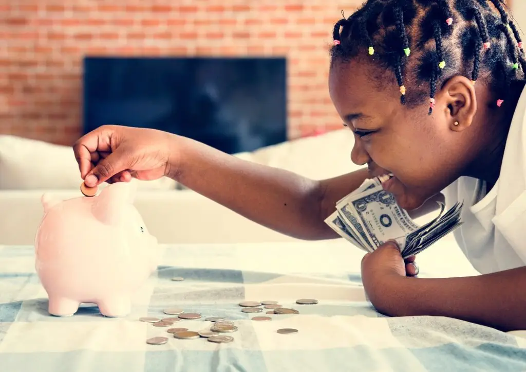Girl putting money in piggy bank.