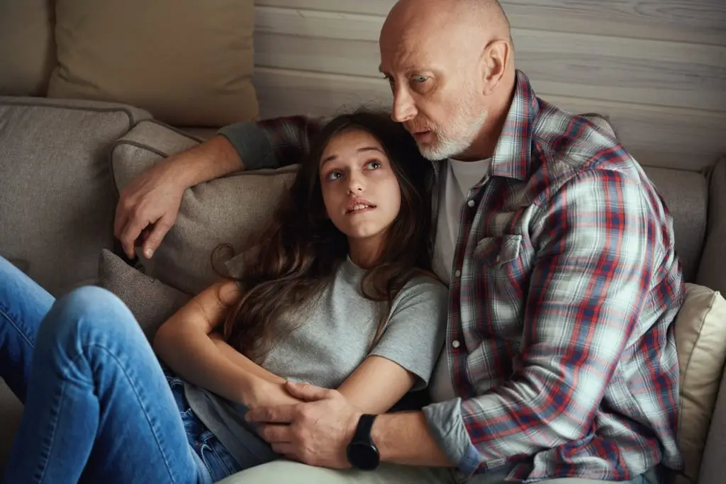 Worried father trying to comfort worried teenage daughter.